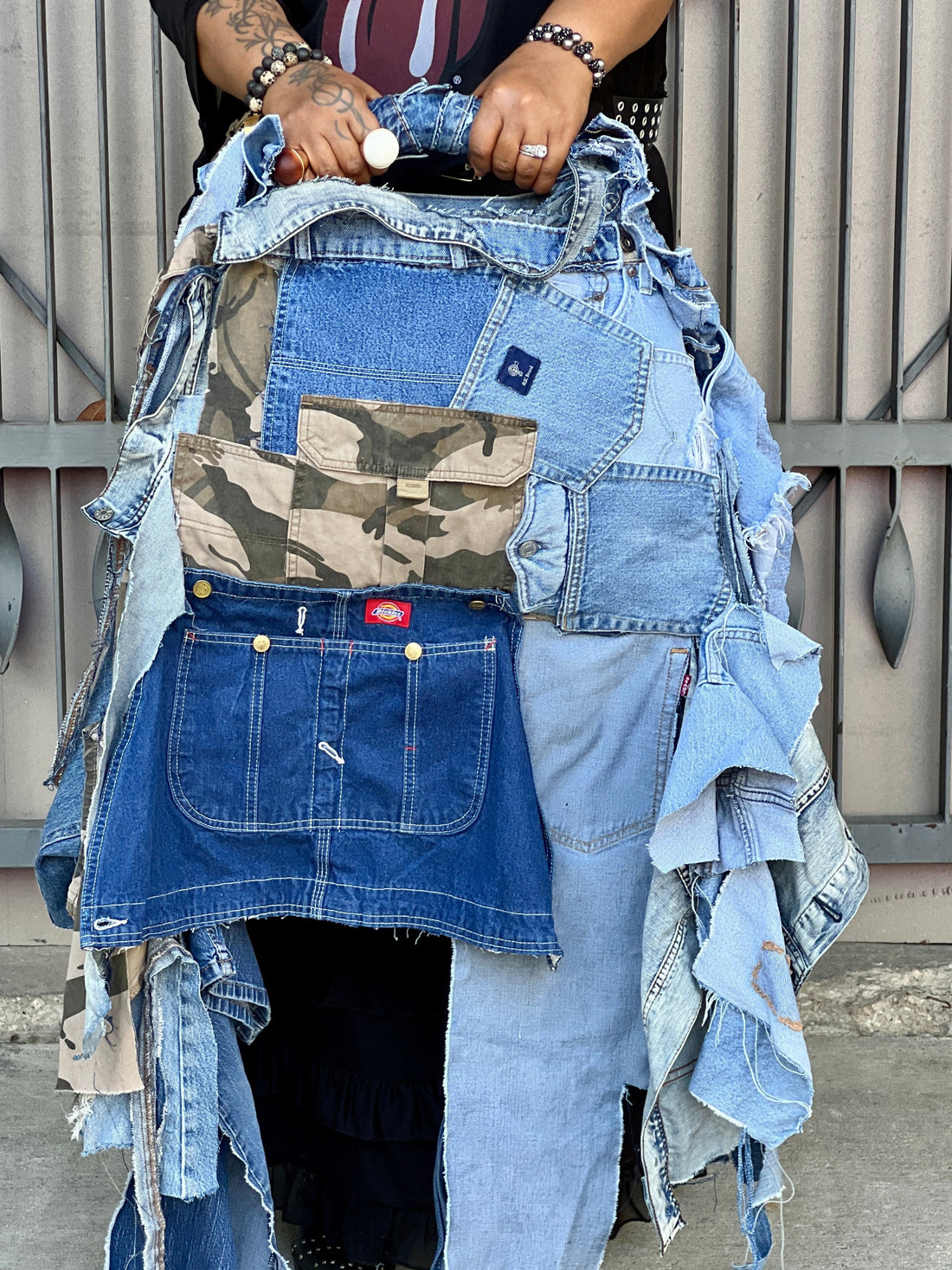 Woman holding Ugly Denim Camo Bag In Front Of metal Building. From Funky Grunge Boutique Collection