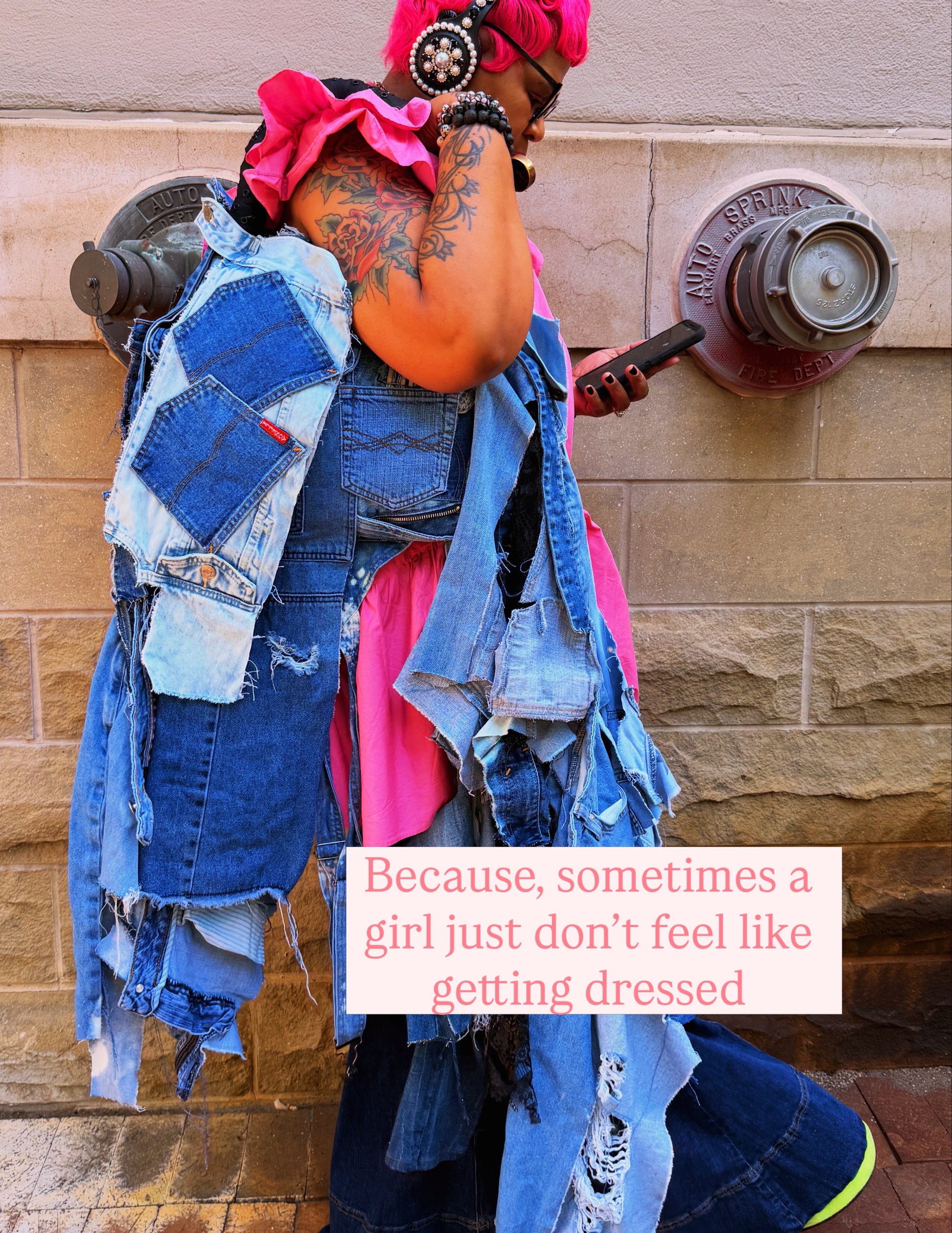 Woman with pink hait leaning on wall showing off her ugly denim bag