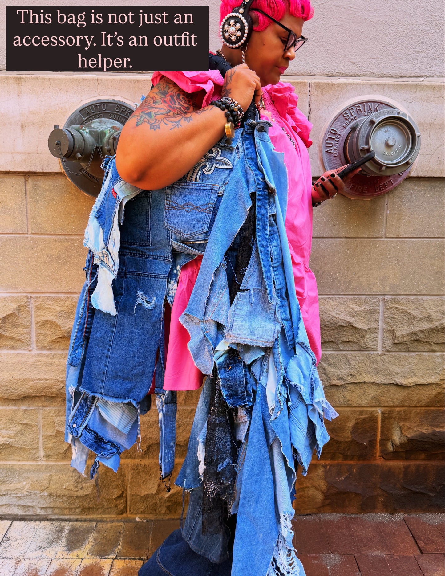woman leaning on wall showing off ugly denim bag with text: this bag is not just an accessory. It's an outfit helper.