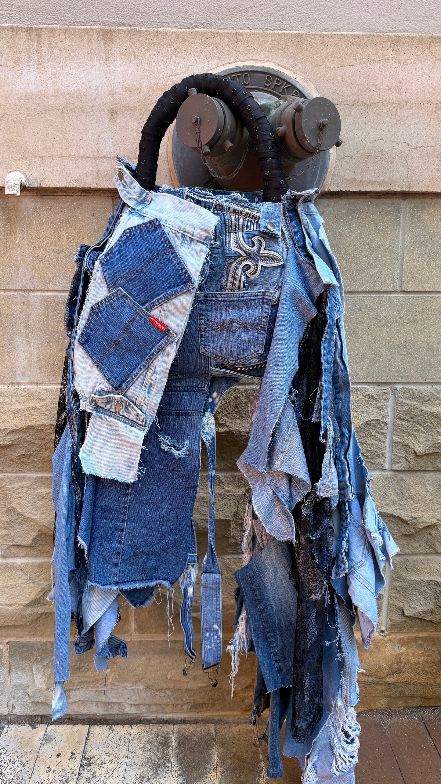 Ugly denim bag with patches hanging on fire hydrant