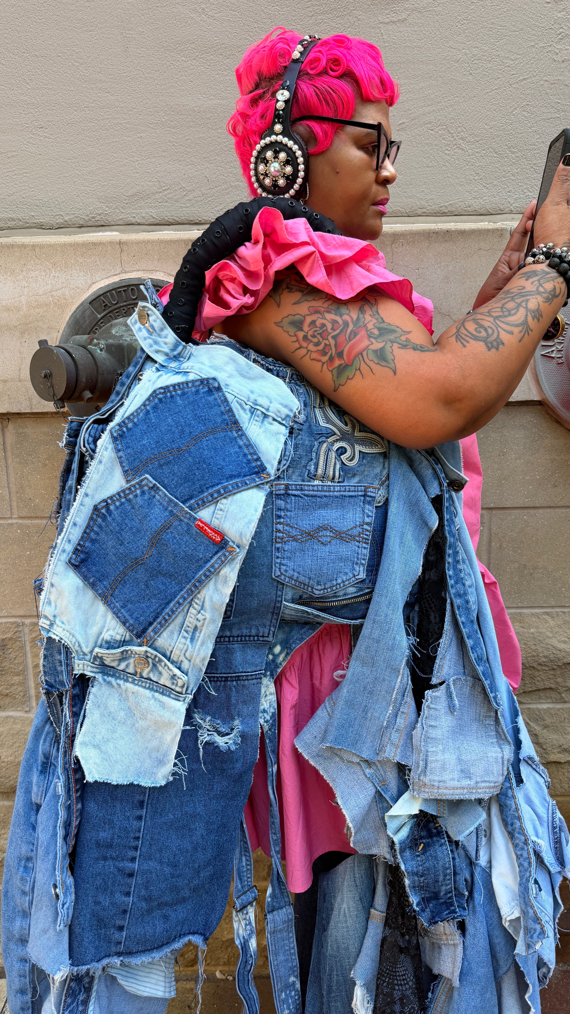 Person wearing an oversized ugly denim janky bag with patchwork pockets, shredded denim strips, black handle, and funky statement styling.