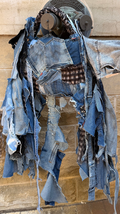 Two-sided handmade upcycled denim bag with mixed blue denim washes, distressed edges, patchwork pockets, and long hanging denim strips.