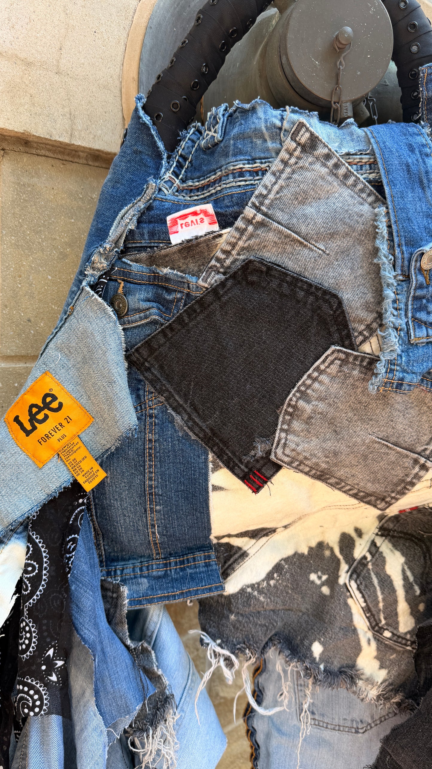 Stack of denim jeans with a Lee brand tag on a textured surface