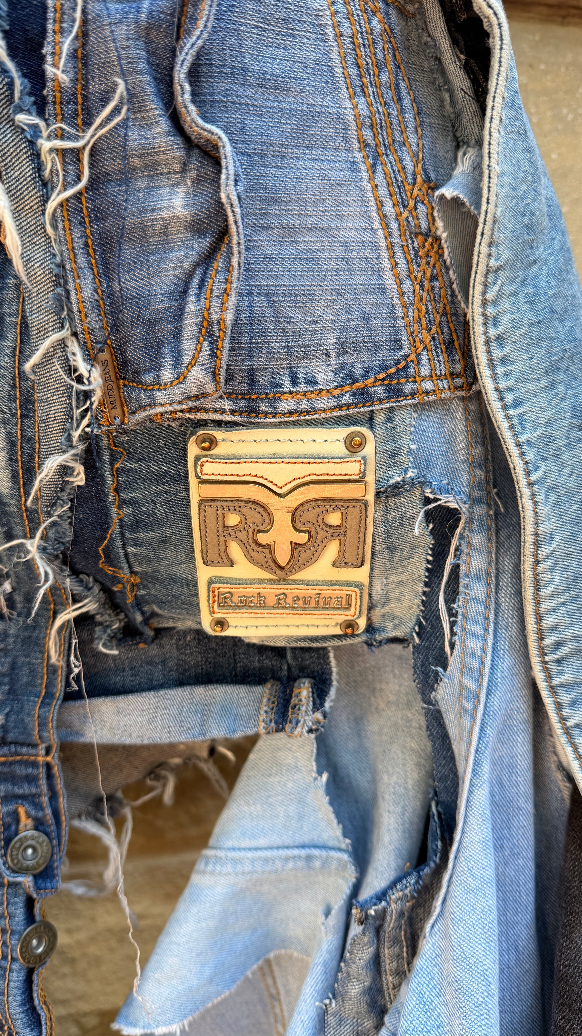 Close-up of a blue denim jacket with a brand logo on a neutral background