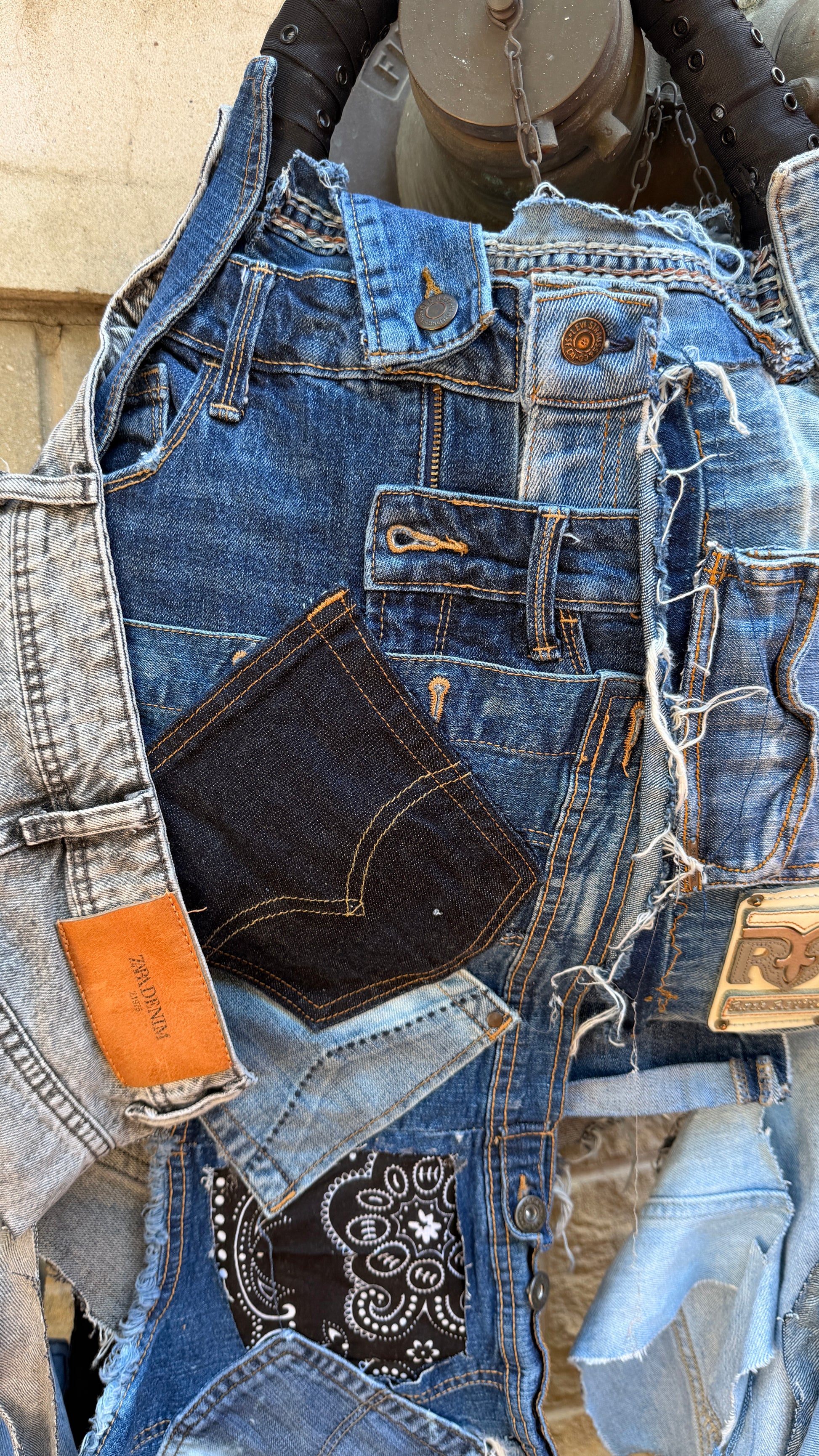 Close-up of handmade upcycled denim bag with frayed blue denim, orange stitching, and Rock Revival label detail.