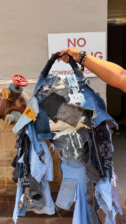 Hand holding a pile of denim bag items with a 'No Towing' sign in the background.