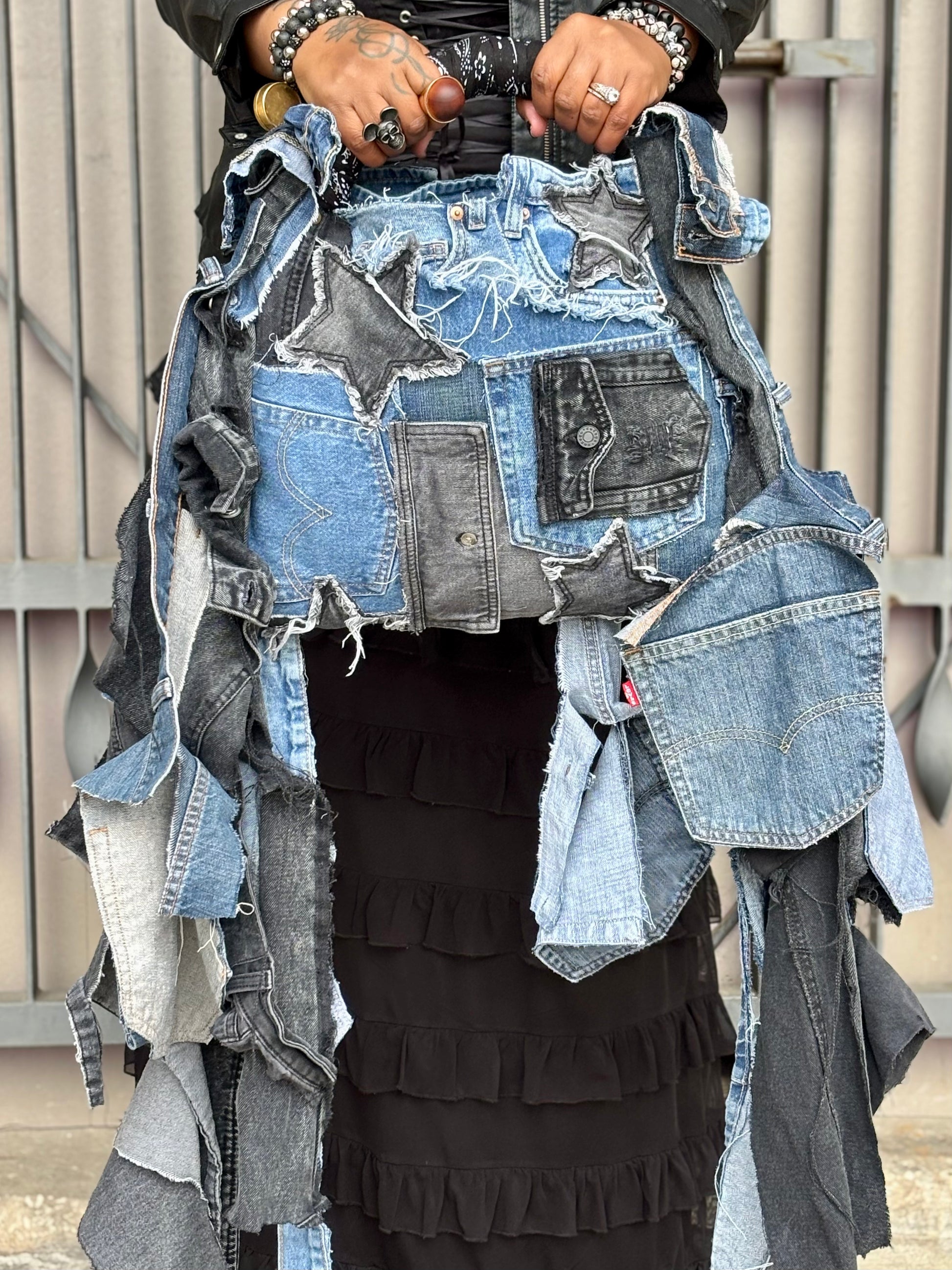 Woman showing a denim shred bag with two tone stars and pockets
