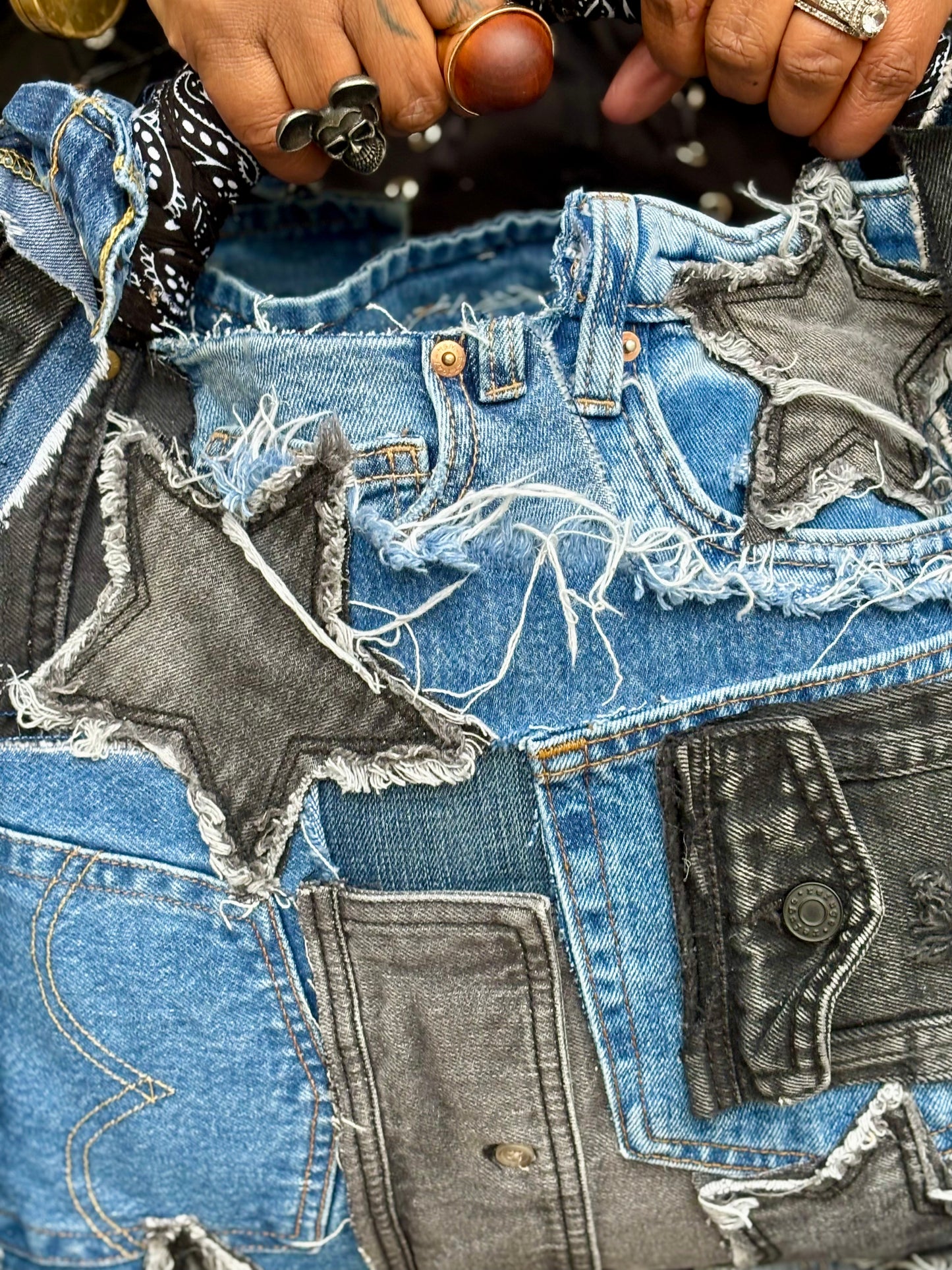 Woman holding denim bag with stars and patches , bandanna handle
