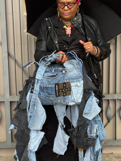 Person holding a black umbrella with a collection of denim pieces.
