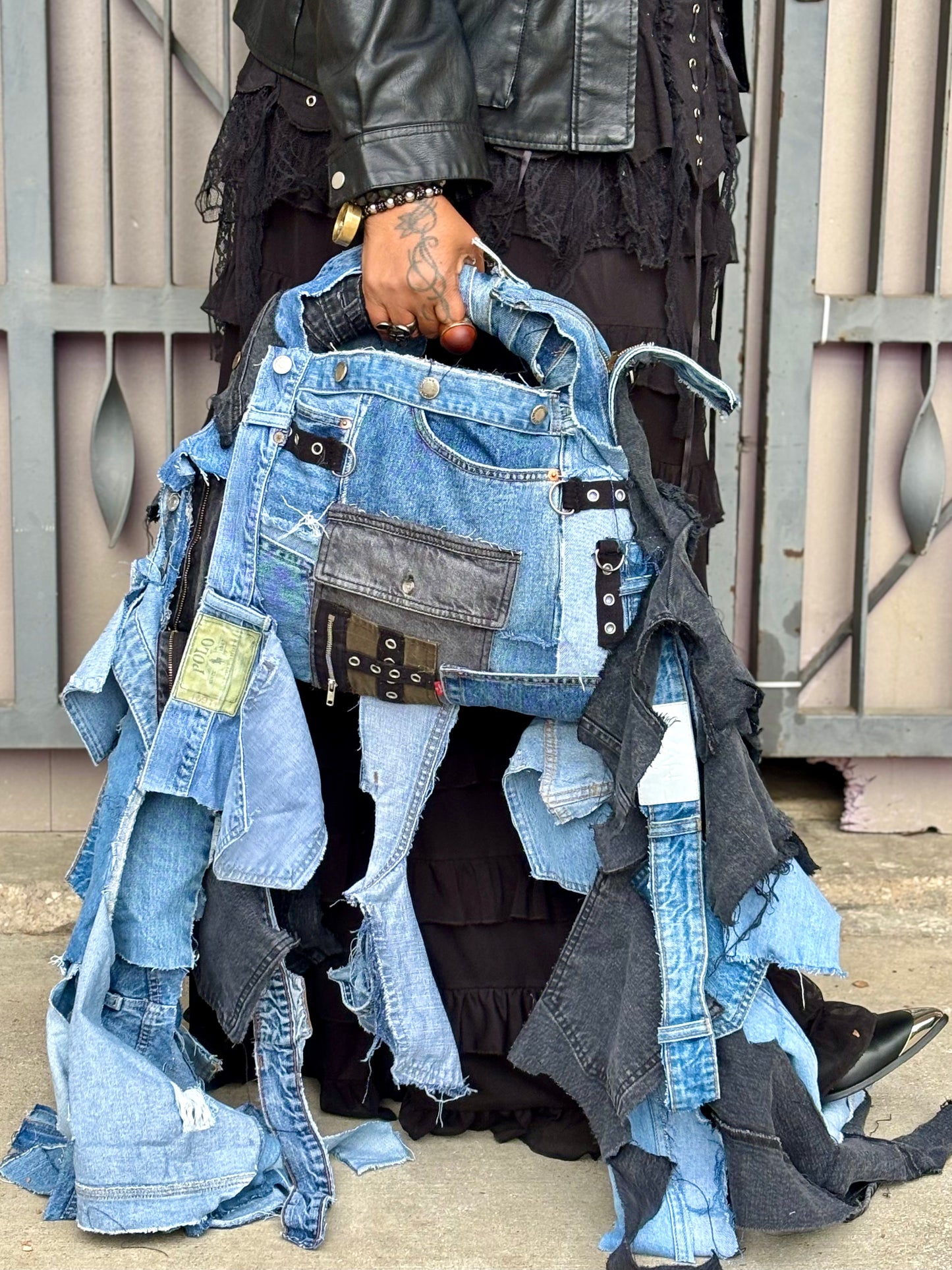 Person holding a denim jbag with patches in an outdoor setting