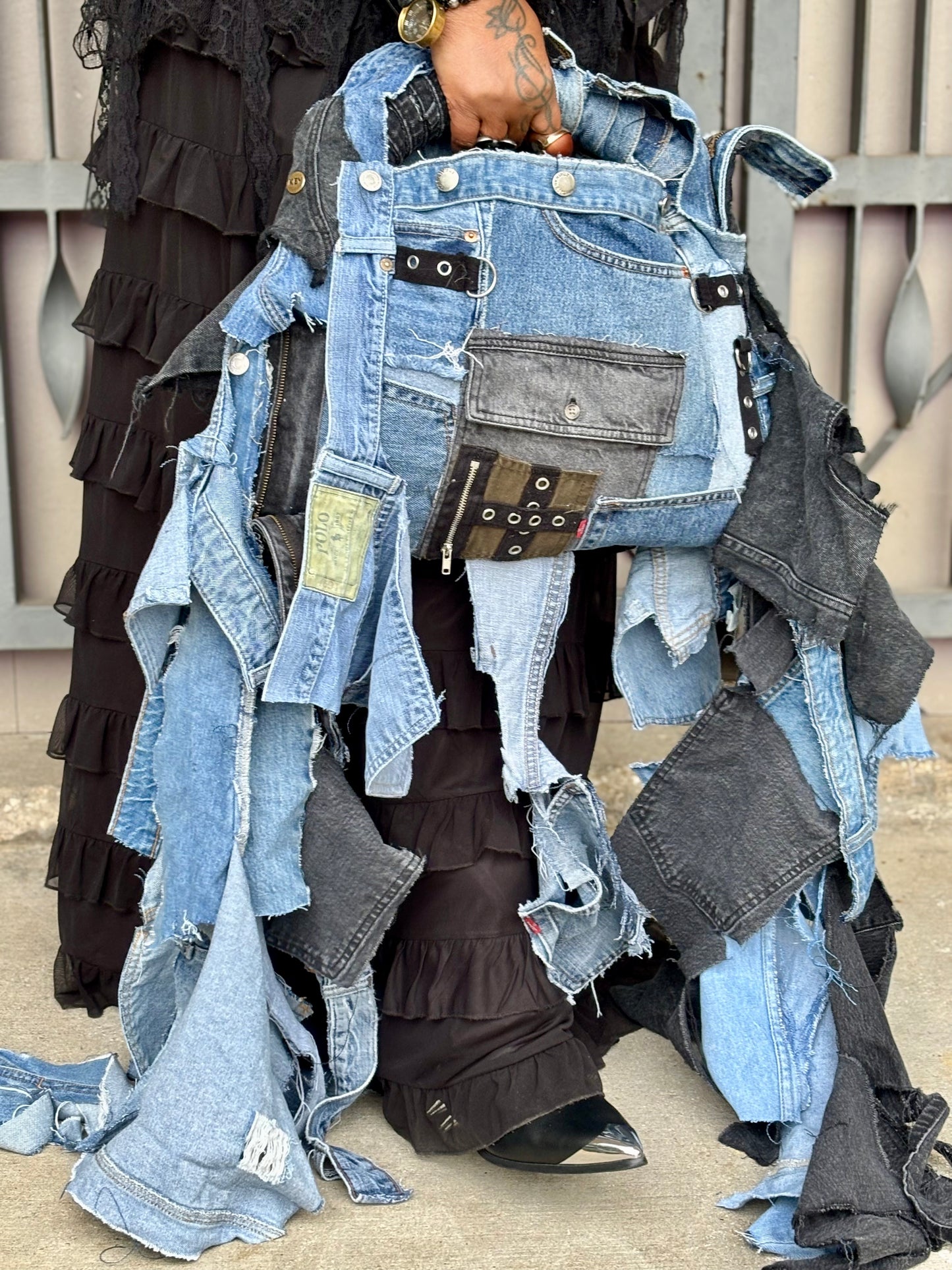 Person wearing a denim  bag made from recycled jeans with a visible brand label.