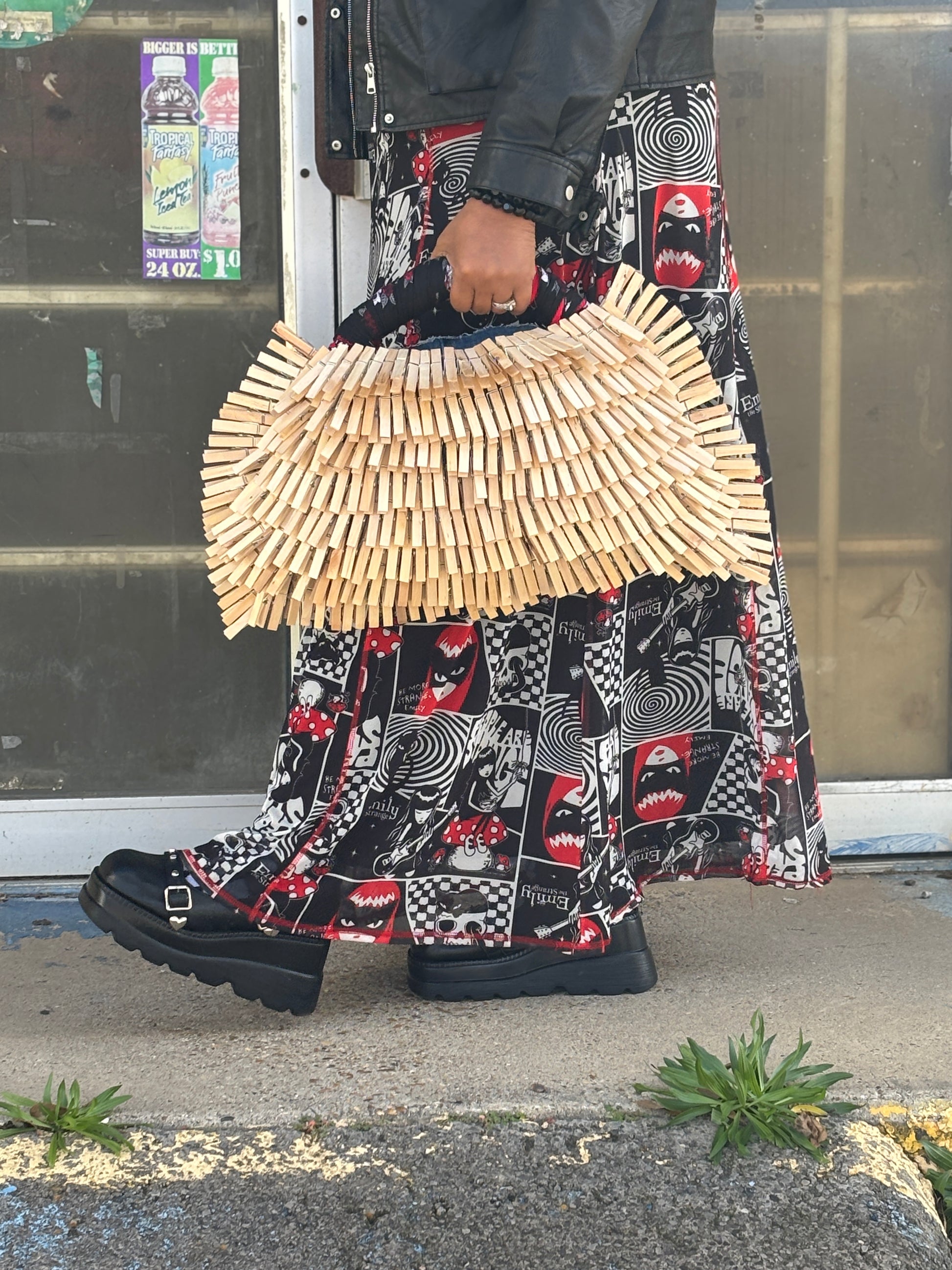 Person holding a wbandanna clothespin denim bag with a patterned skirt and shoes.