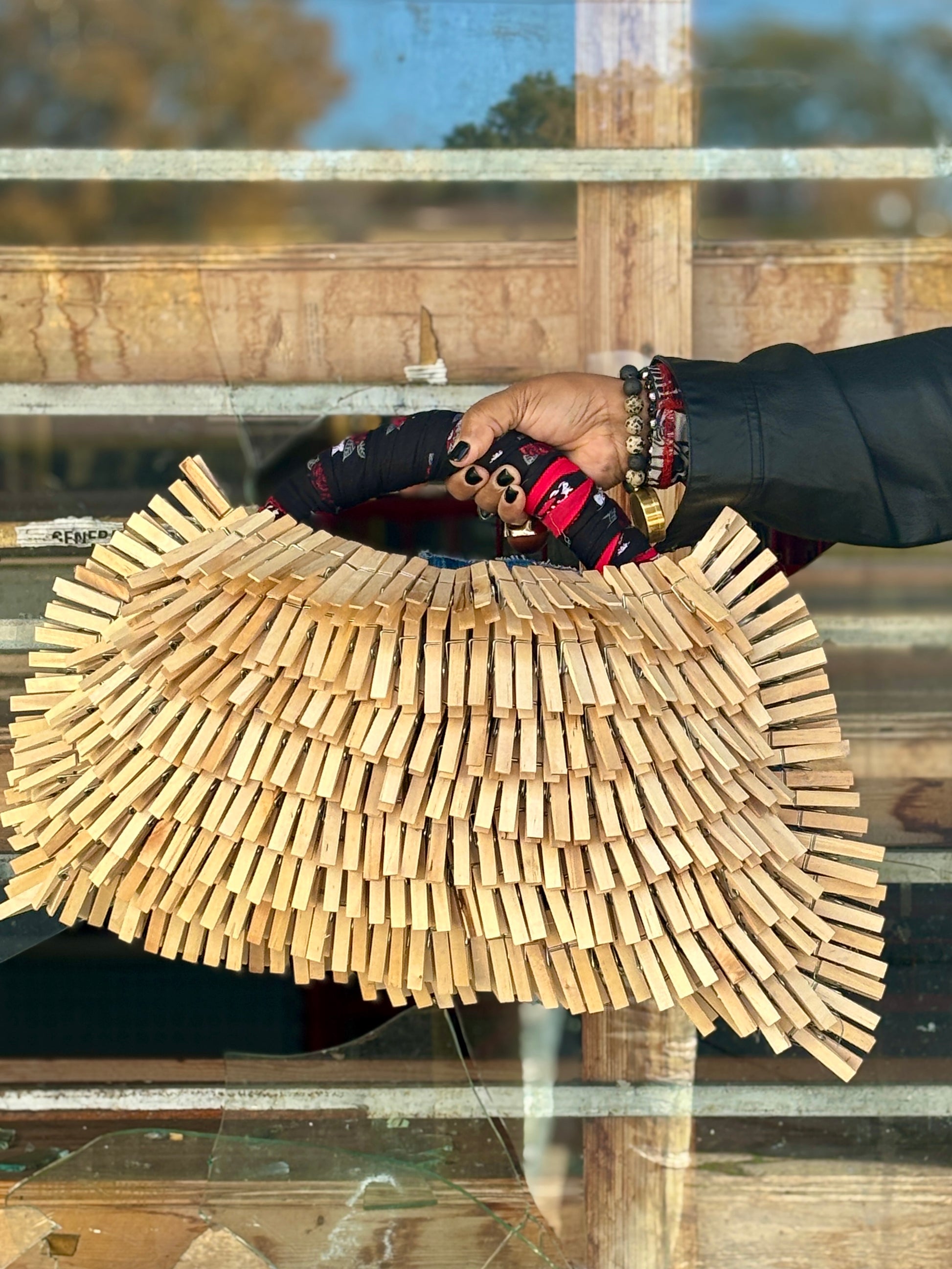 Hand holding a clothespin denm bag with bandanna handle and with a blurred background