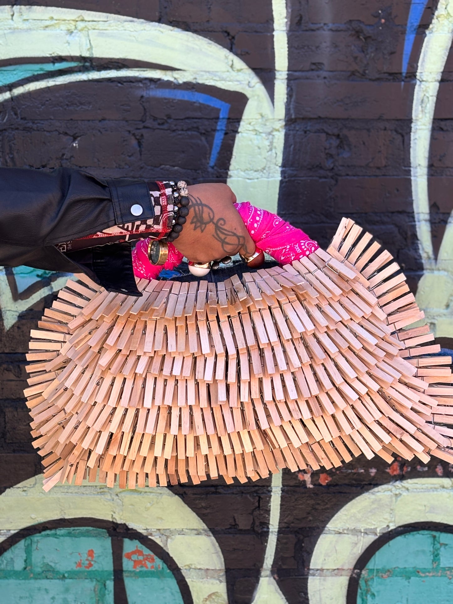clothespin denim bag held by a person against a graffiti-covered wall.